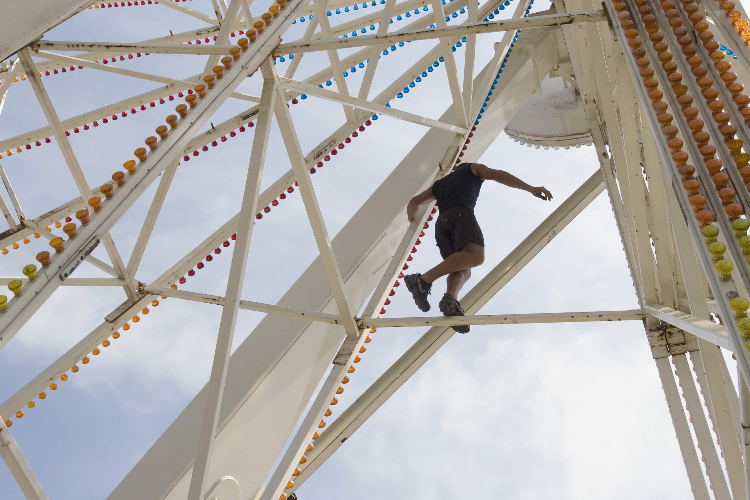 Worker balancing on Ferris wheel framework at a county fair